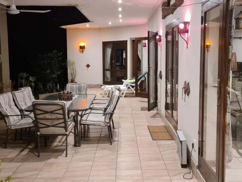 A spacious covered patio area featuring tiled flooring, recessed lighting, and multiple glass door access points to the interior living spaces.