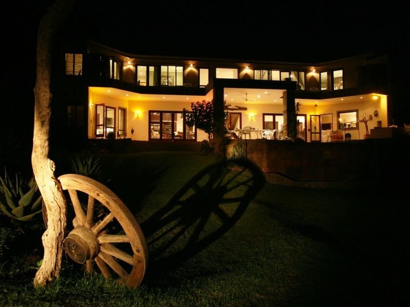 Night view of the rear elevation featuring a spacious covered patio, extensive glass sliding doors, and warm exterior accent lighting.