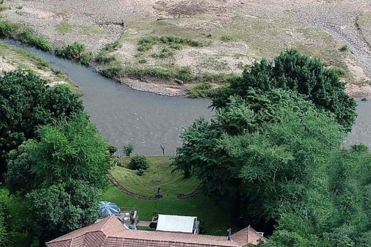 Aerial view of a residential property featuring a tiled roof, established garden, and direct access to a river landscape.