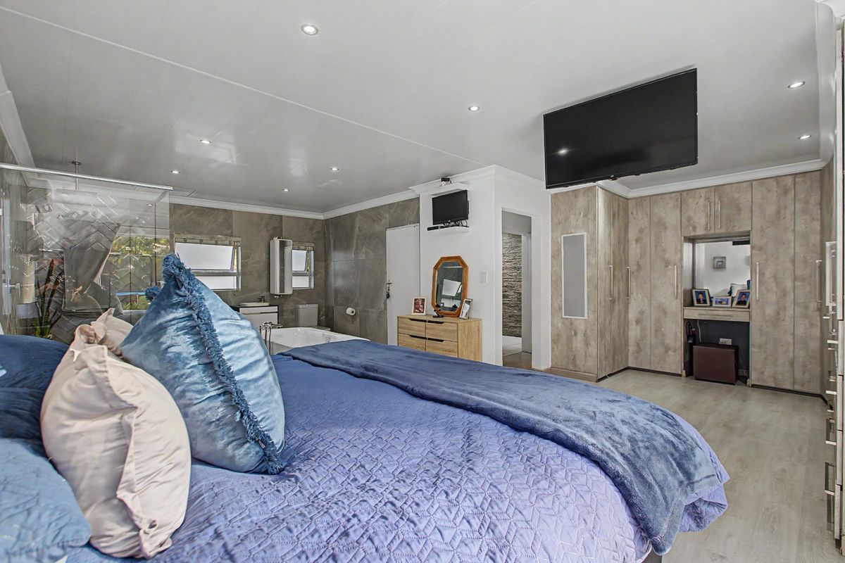 Spacious bedroom featuring integrated cabinetry, recessed ceiling lighting, and an open-plan en-suite bathroom with modern tiling and a soaking tub.