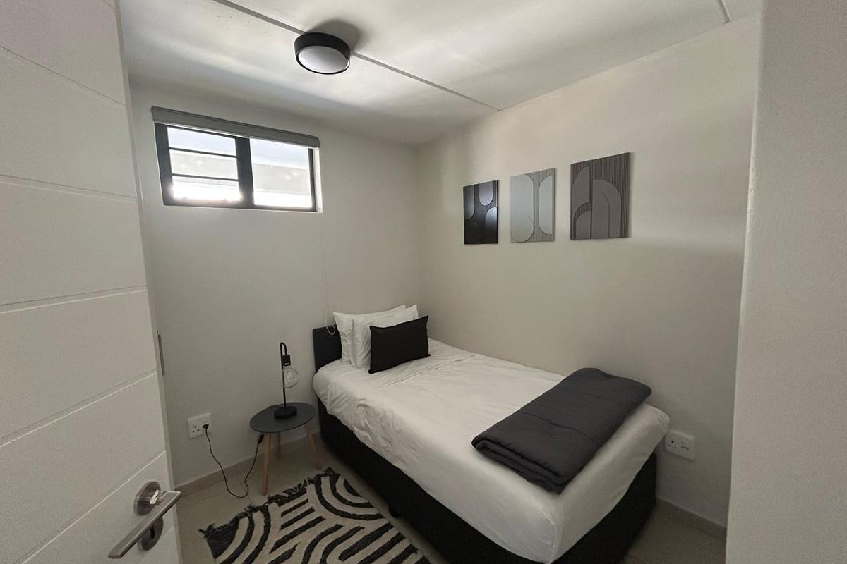 A compact bedroom featuring tiled flooring, a horizontal window, and a modern ceiling light fixture.