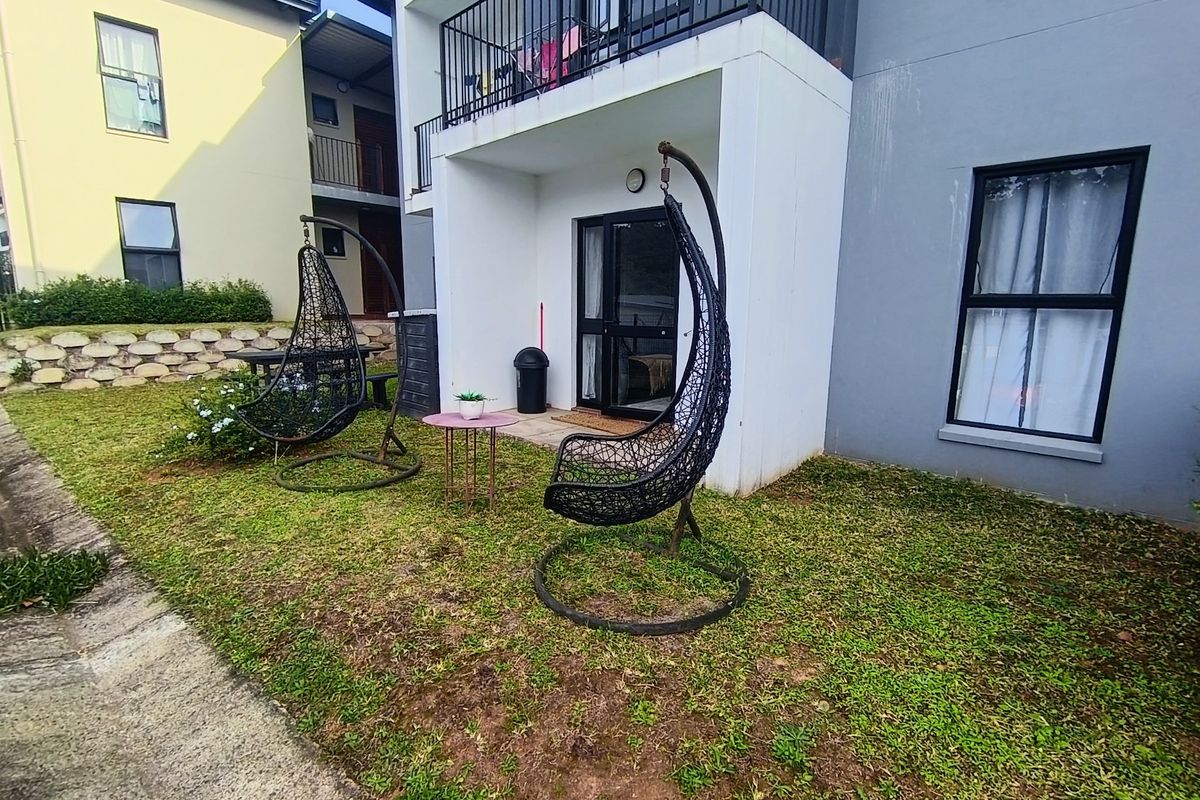 Ground floor apartment exterior featuring a small private garden area and a covered patio with access to the living space.