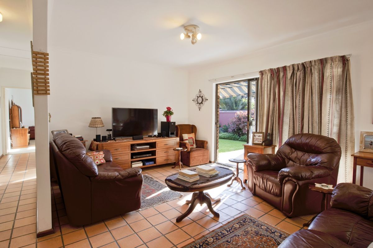 A comfortable living room featuring terracotta floor tiles and sliding glass doors that provide direct access to the rear garden.