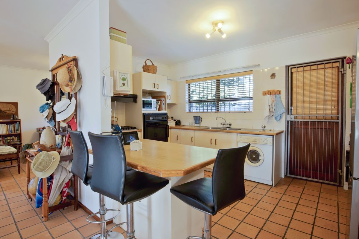 Functional kitchen featuring built-in cabinetry, integrated oven, cooktop, and a breakfast bar, with direct access to an external security door.