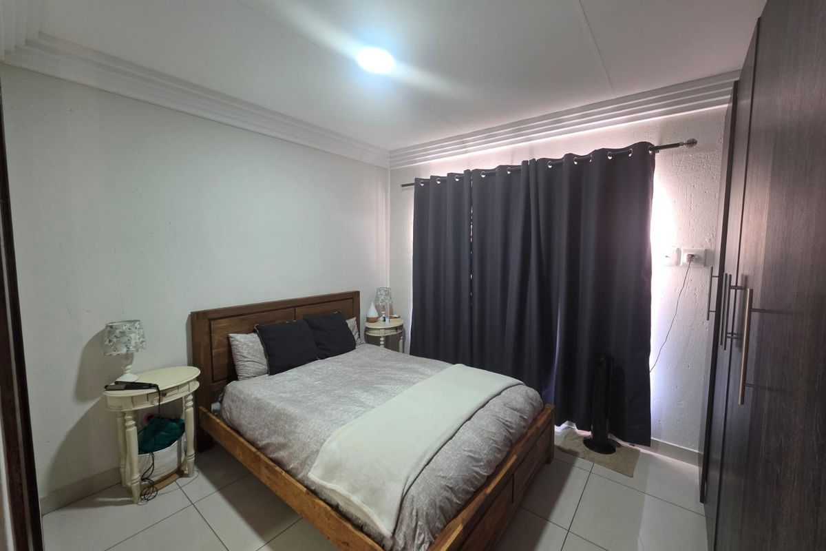 A bedroom featuring tiled flooring, built-in cupboards, and crown molding, providing a functional and comfortable living space.