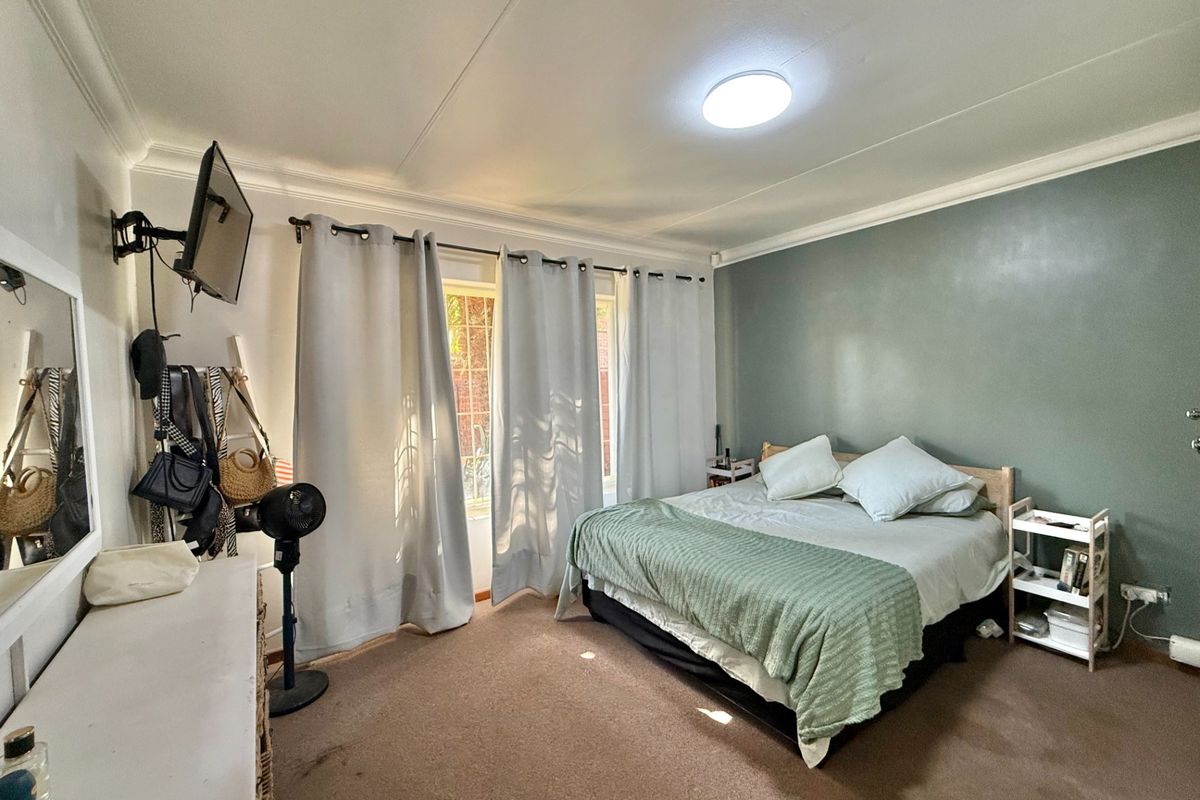 A spacious bedroom featuring neutral carpeting, a feature wall, and direct access to an outdoor area through sliding glass doors.