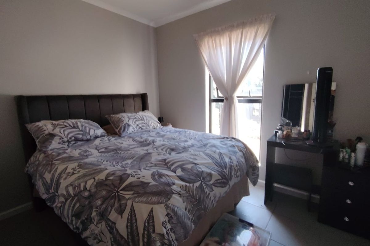 A well-lit bedroom featuring tiled flooring and a window with neutral curtains, providing a comfortable and functional living space.
