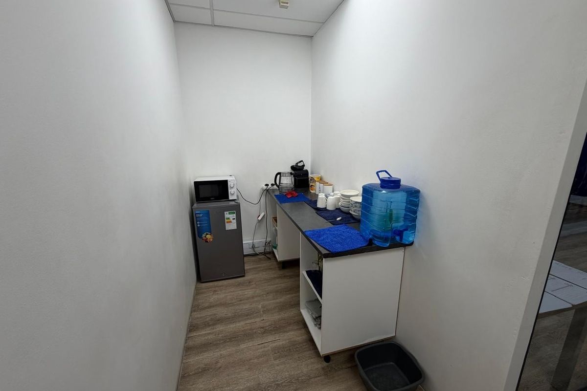 A compact office kitchenette area featuring a small counter, cabinetry, and space for a mini-fridge and microwave.