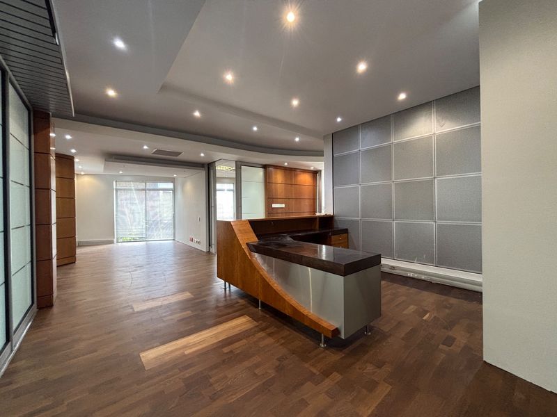 Modern office space featuring a built-in reception desk, hardwood flooring, recessed lighting, and contemporary metal and wood wall paneling.