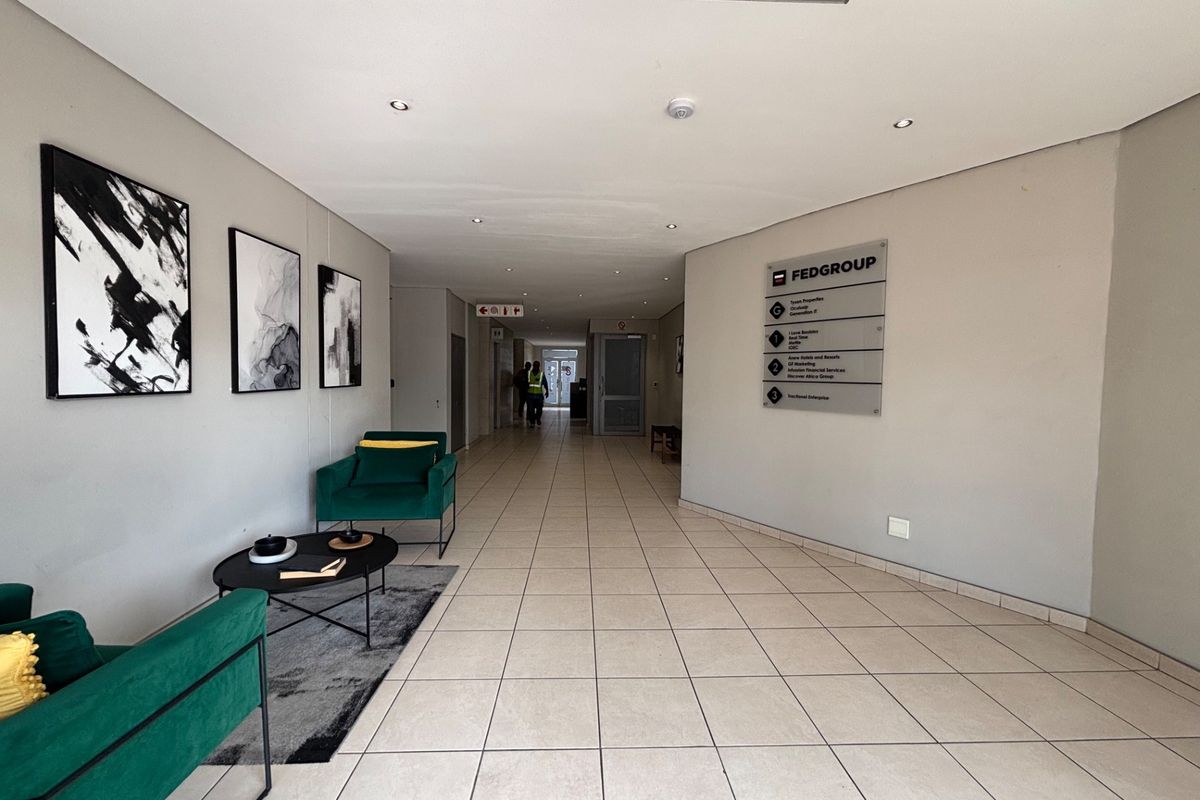 A bright and professional office building hallway featuring ceramic floor tiles, recessed lighting, and a wall-mounted directory sign for tenants.