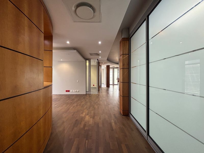 Modern office interior featuring high-quality parquet flooring, curved wood paneling, and frosted glass partitions, creating a professional and spacious work environment.