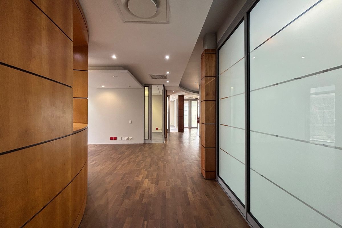 Modern office interior featuring high-quality parquet flooring, curved wood paneling, and frosted glass partitions, creating a professional and spacious work environment.