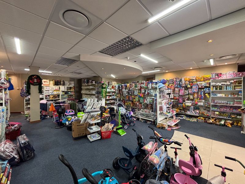 A retail space featuring a suspended ceiling with recessed lighting, carpeted flooring, and extensive built-in shelving units for product display.