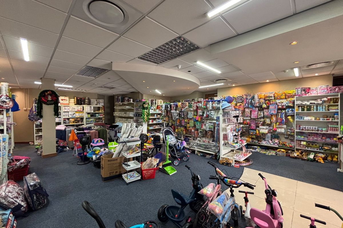 A retail space featuring a suspended ceiling with recessed lighting, carpeted flooring, and extensive built-in shelving units for product display.