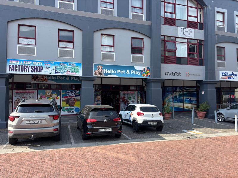 Front exterior view of a multi-tenant commercial retail building featuring storefronts with large display windows and dedicated paved parking bays.