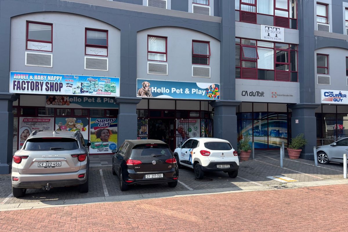 Front exterior view of a multi-tenant commercial retail building featuring storefronts with large display windows and dedicated paved parking bays.