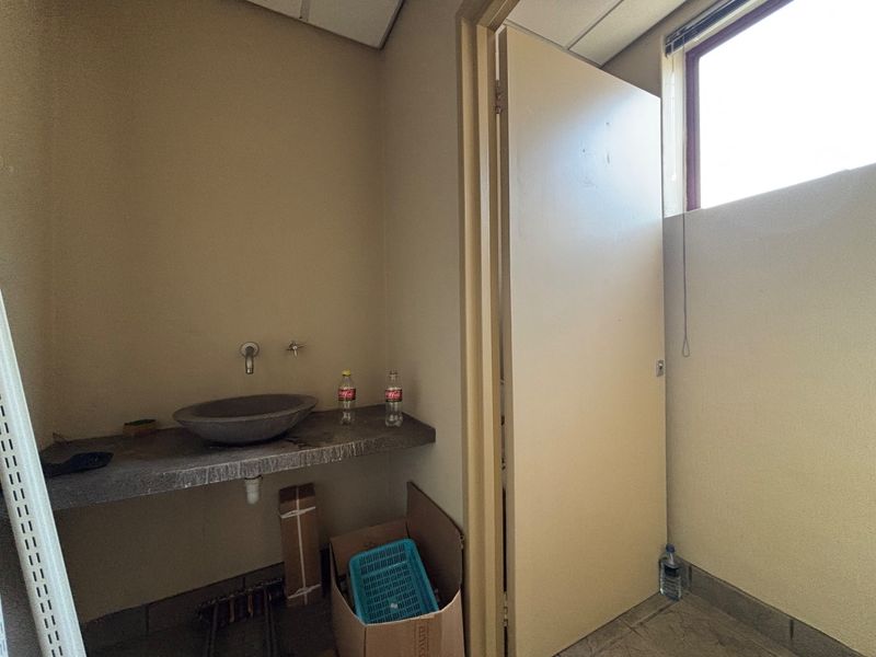 A functional utility space featuring a stone basin set into a concrete countertop with wall-mounted plumbing fixtures.