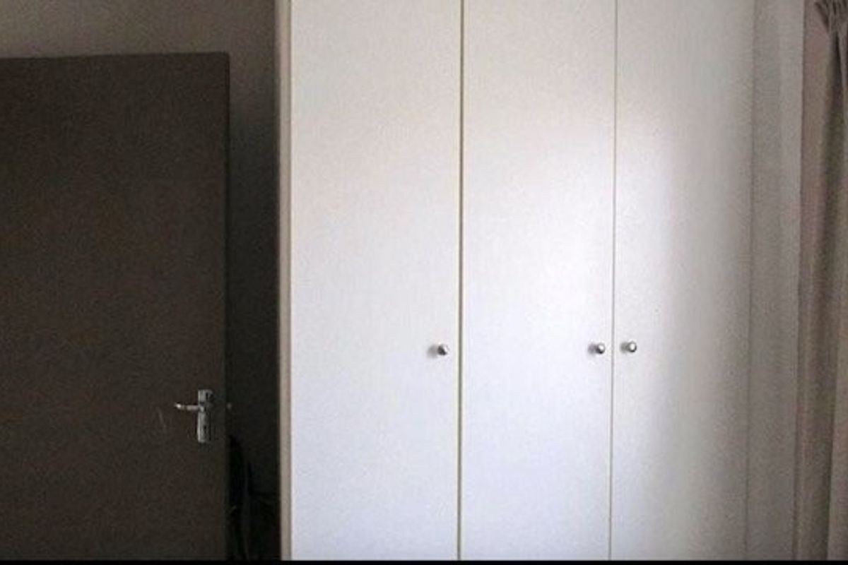 A bedroom interior featuring built-in white cabinetry and a dark-toned door.