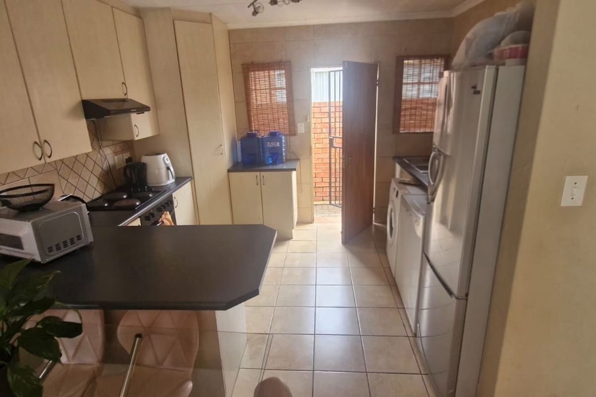A functional kitchen featuring built-in cabinetry, a breakfast bar, tiled flooring, and direct access to an outdoor area.