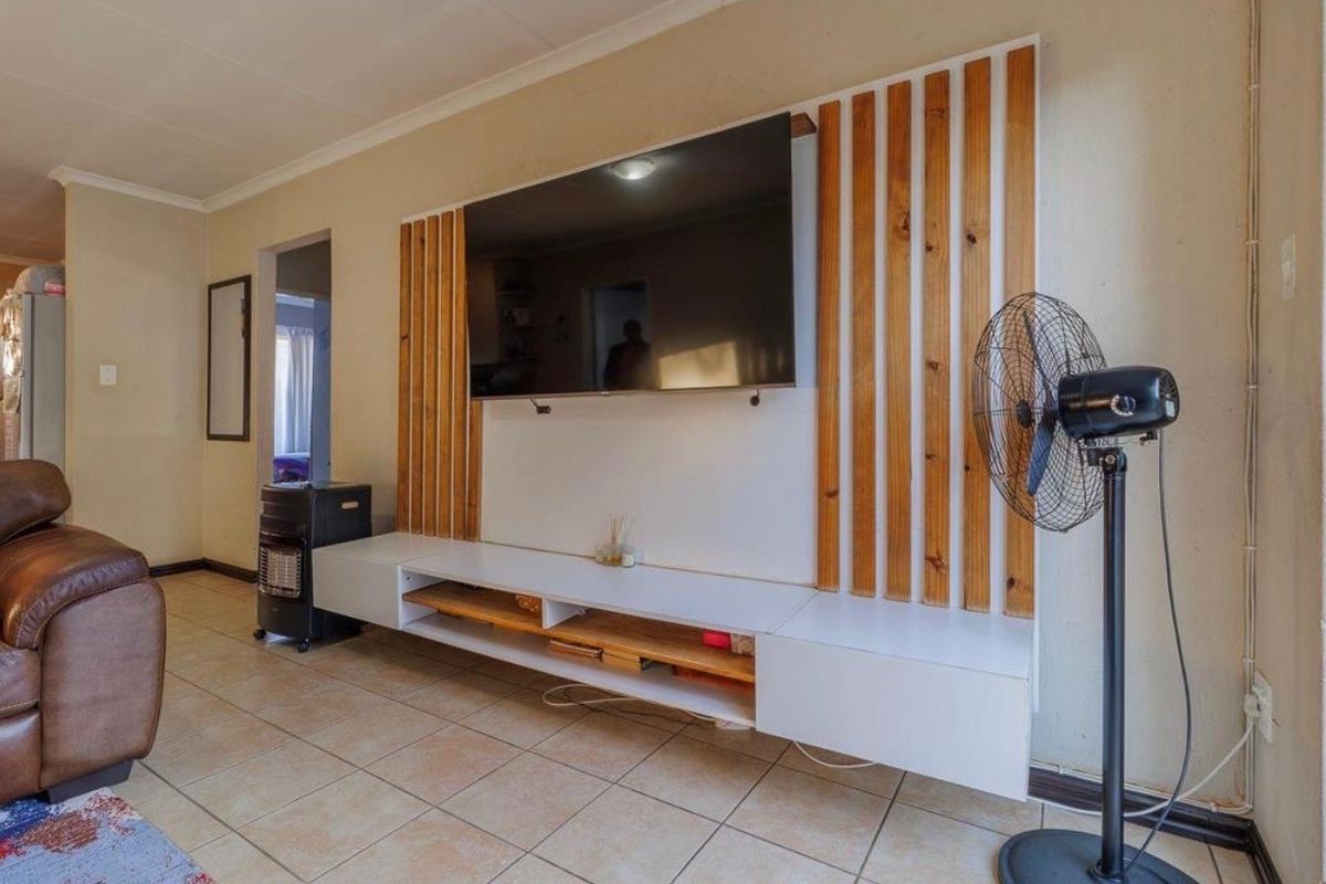 A living room featuring a modern, custom-built wall-mounted entertainment unit with vertical timber slat detailing and integrated shelving.
