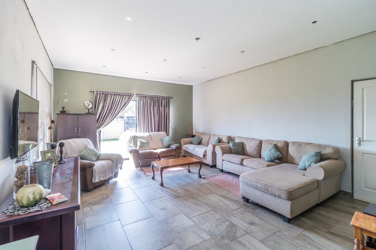 Spacious living room featuring large format floor tiles, recessed downlighting, and direct access to the outdoor area through sliding glass doors.