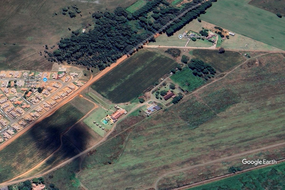 Aerial view of the farm property showing multiple buildings, a swimming pool, cultivated land, and surrounding rural landscape.