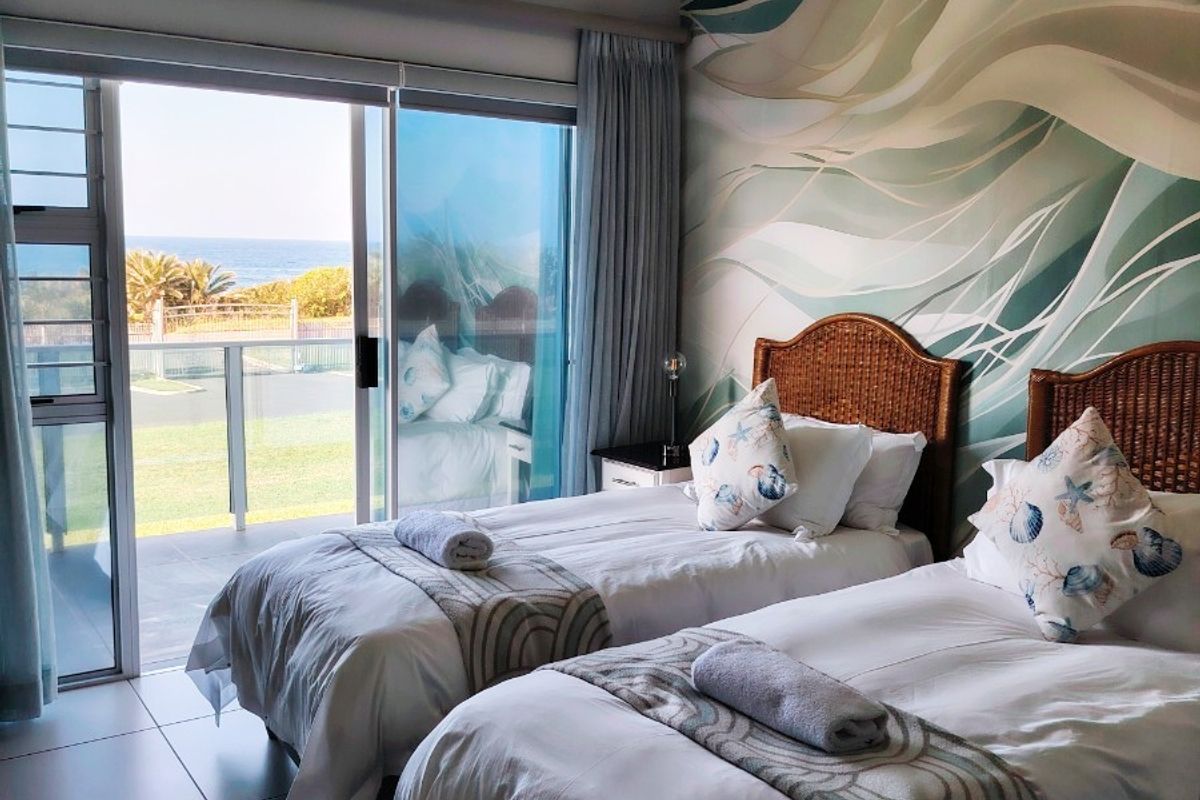A well-maintained bedroom featuring tiled floors, a ceiling fan, and large sliding glass doors that open onto a balcony with ocean views.