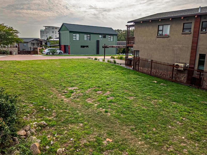 A vacant residential plot of land situated within a developed estate, featuring established grass cover and surrounding residential properties.