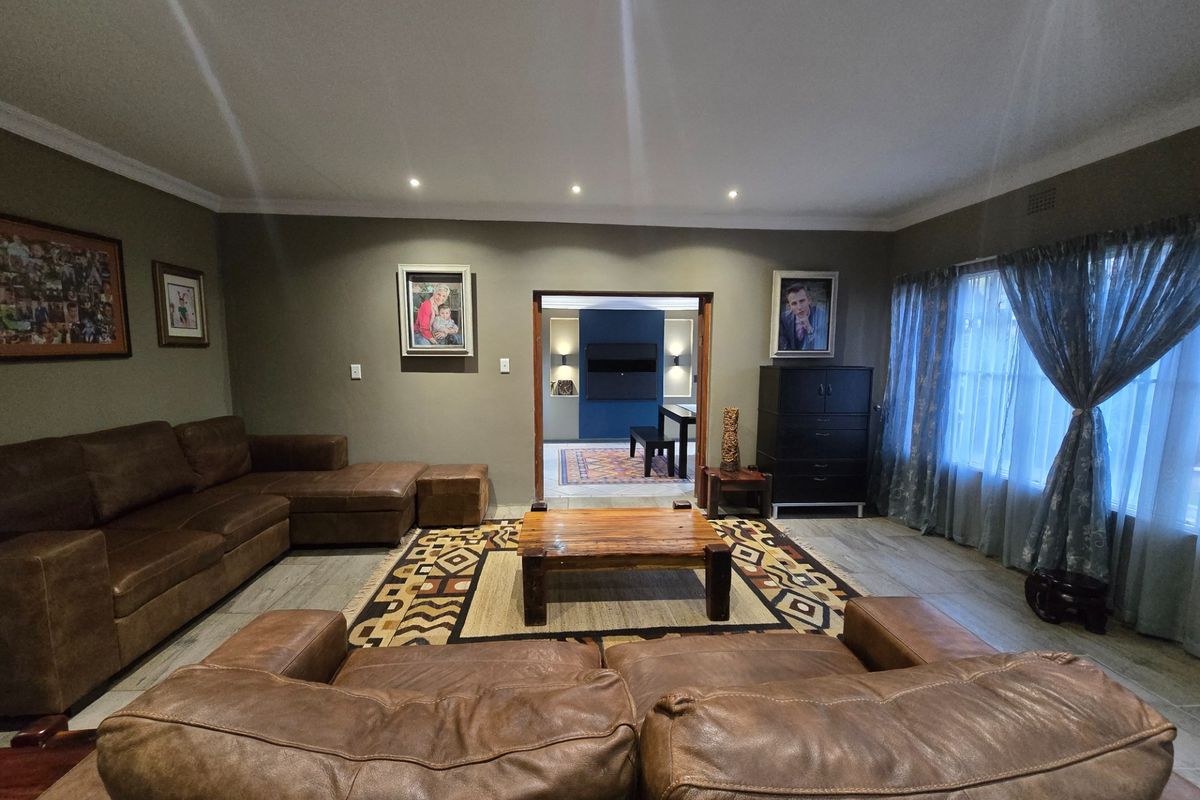 Spacious living room featuring tiled flooring, recessed downlighting, and a wide doorway leading to an adjacent dining area.