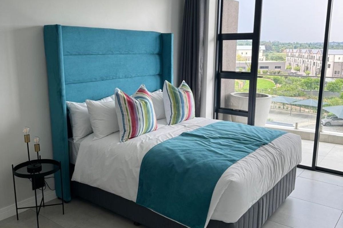 Modern bedroom featuring large format floor tiles and a floor-to-ceiling sliding glass door providing natural light and access to an outdoor balcony.
