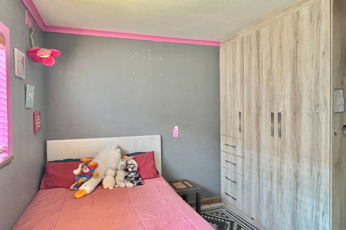 A bedroom featuring a light wood-grain built-in wardrobe with integrated drawers and hanging space.
