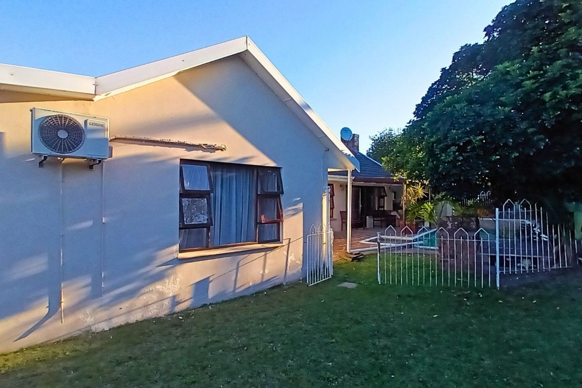 View of the rear exterior of the house featuring a lawn, metal fencing, and an external air conditioning unit.