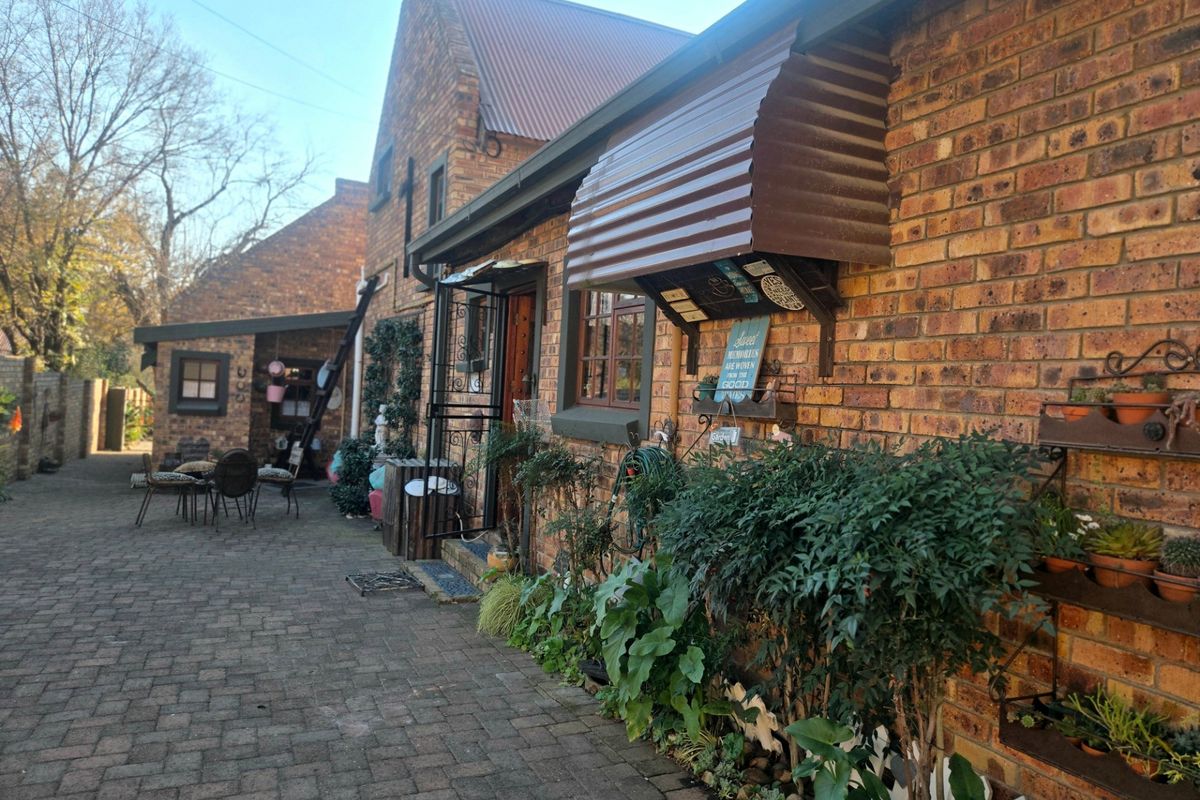 A charming rear courtyard featuring face brick walls, a corrugated metal awning, and paved flooring, providing a private outdoor space.