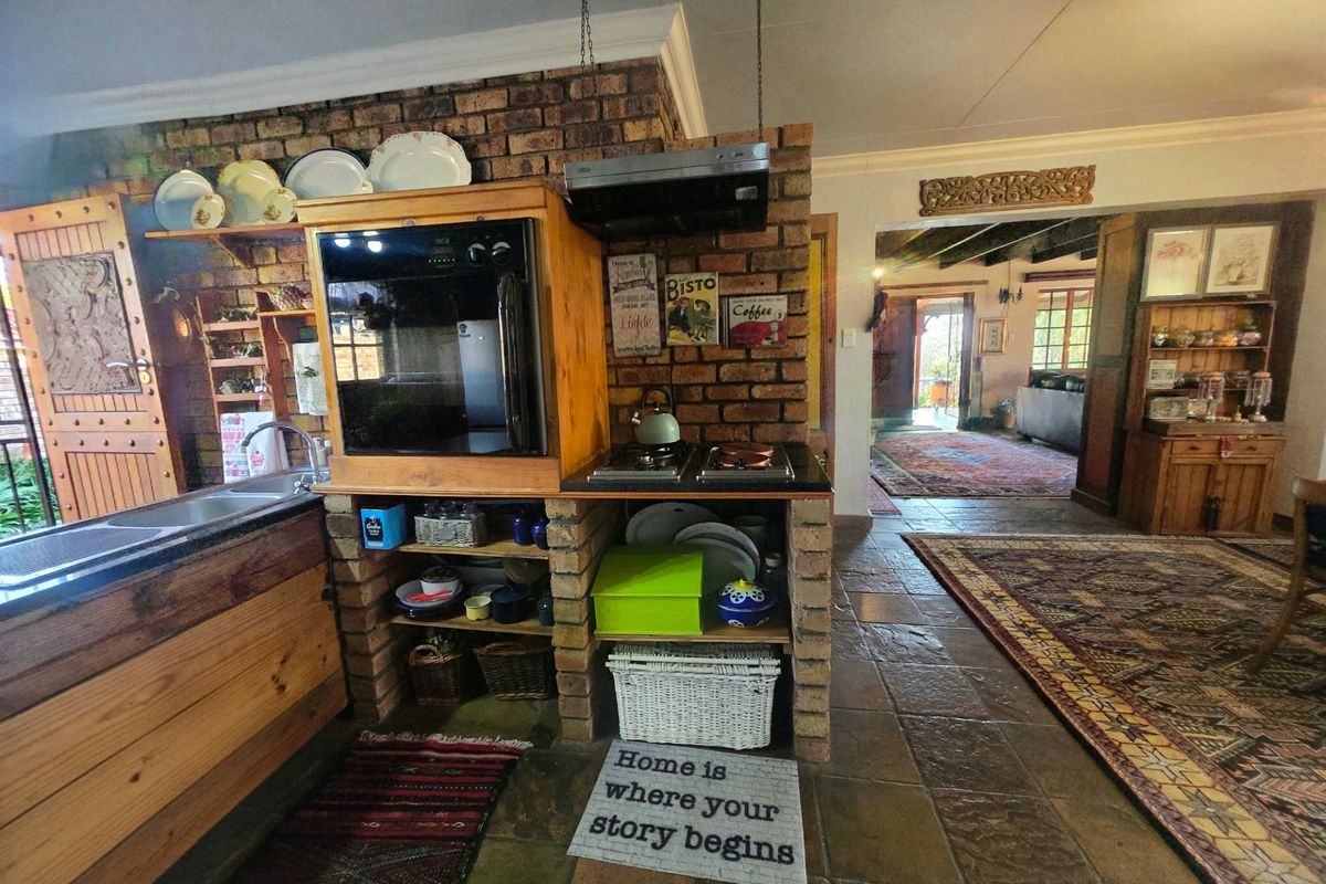 Rustic kitchen featuring a brick-built island with integrated oven, hob, and extractor fan, complemented by stone tile flooring and open shelving.