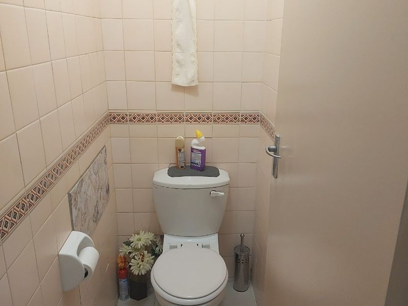 A compact guest toilet featuring floor-to-ceiling ceramic wall tiles, a standard white toilet suite, and an integrated extractor fan.
