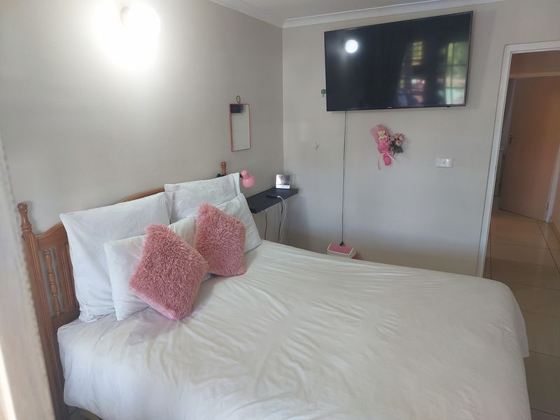 A bedroom featuring tiled flooring, neutral wall paint, and a wall-mounted television.