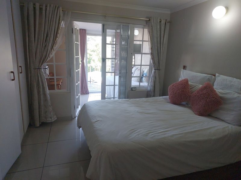 A bedroom featuring tiled flooring, built-in cupboards, and French doors providing direct access to an outdoor balcony area.