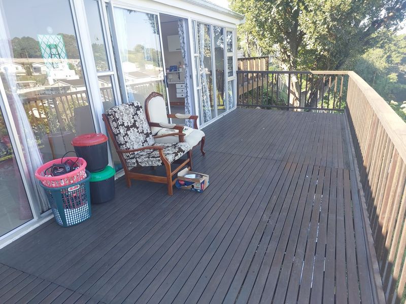 Spacious elevated timber deck featuring sliding glass door access, wooden balustrades, and views of the surrounding trees.