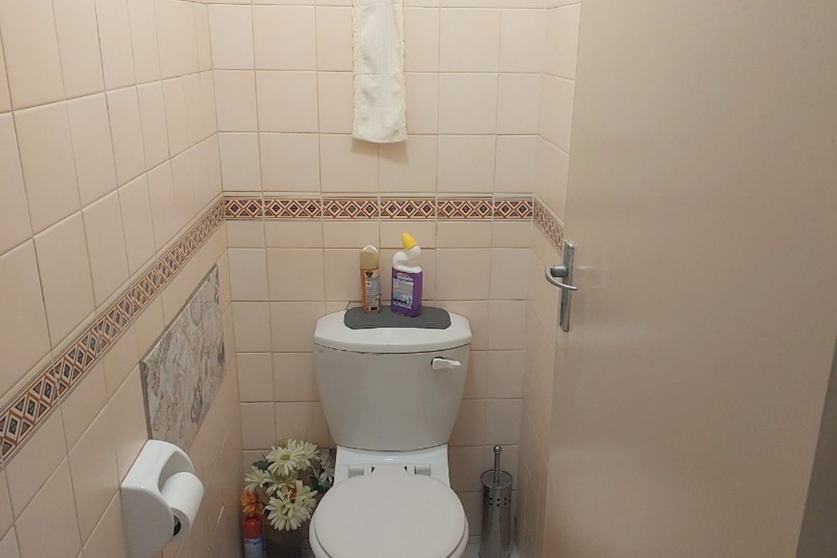 A compact guest toilet featuring floor-to-ceiling ceramic wall tiles, a standard white toilet suite, and an integrated extractor fan.