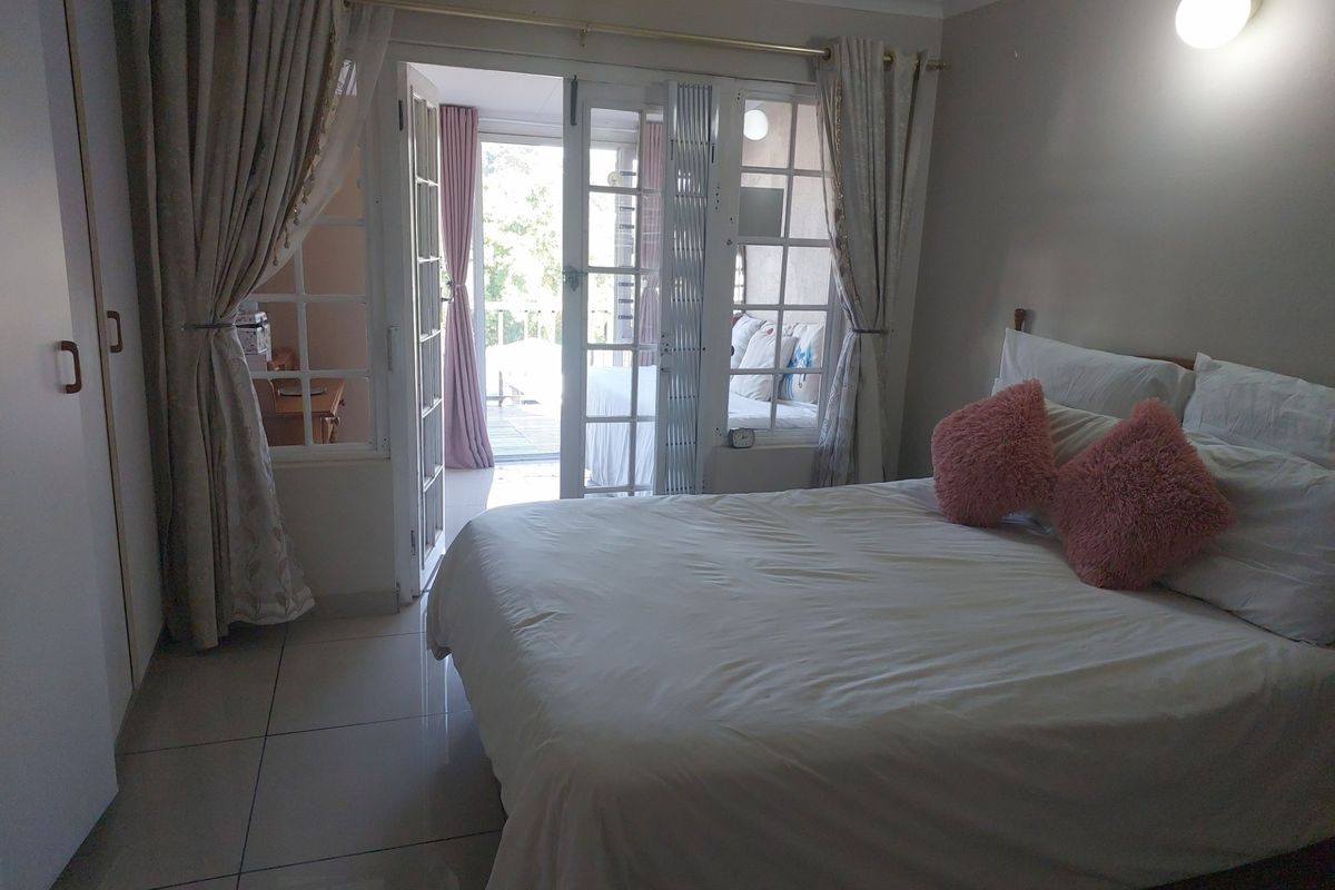 A bedroom featuring tiled flooring, built-in cupboards, and French doors providing direct access to an outdoor balcony area.