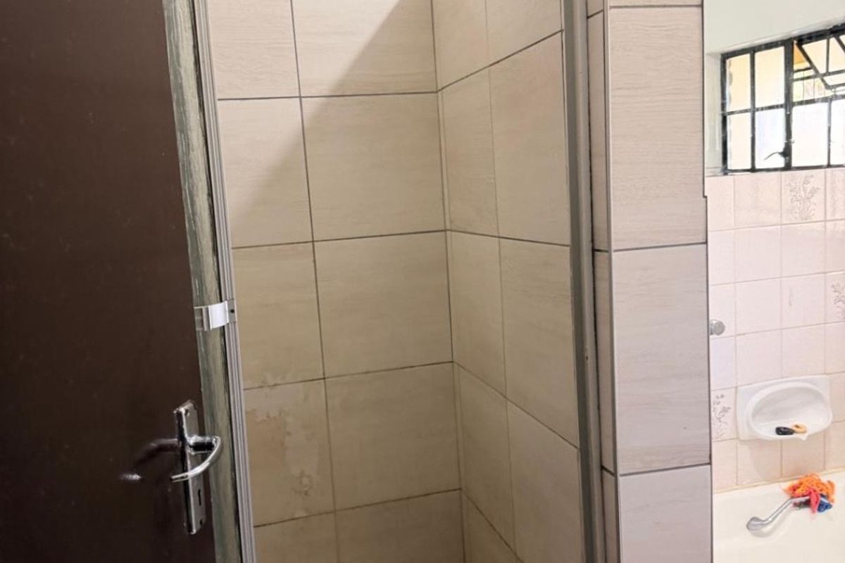 A functional bathroom featuring a tiled shower enclosure with a glass door and a separate bathtub with wall-mounted fixtures.