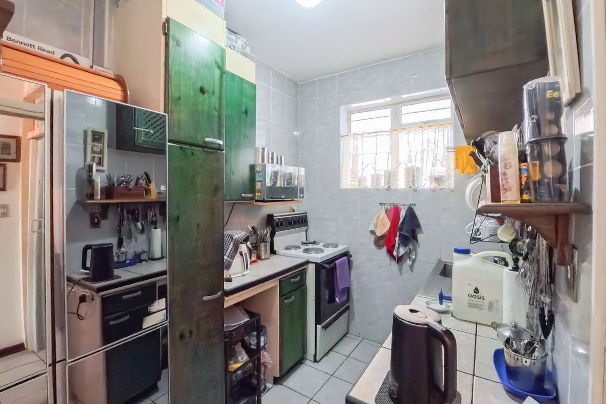 Compact kitchen featuring tiled walls and flooring, built-in cabinetry, and a freestanding stove, offering a functional layout for efficient meal preparation.