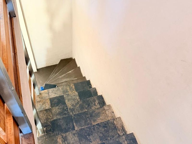 A staircase featuring dark slate-style tiled steps and a wooden handrail, providing access between levels in the apartment.