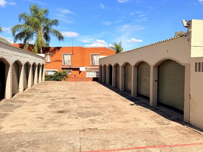 A view of the apartment complex garage area featuring multiple secure parking bays with arched architectural detailing and concrete driveway.