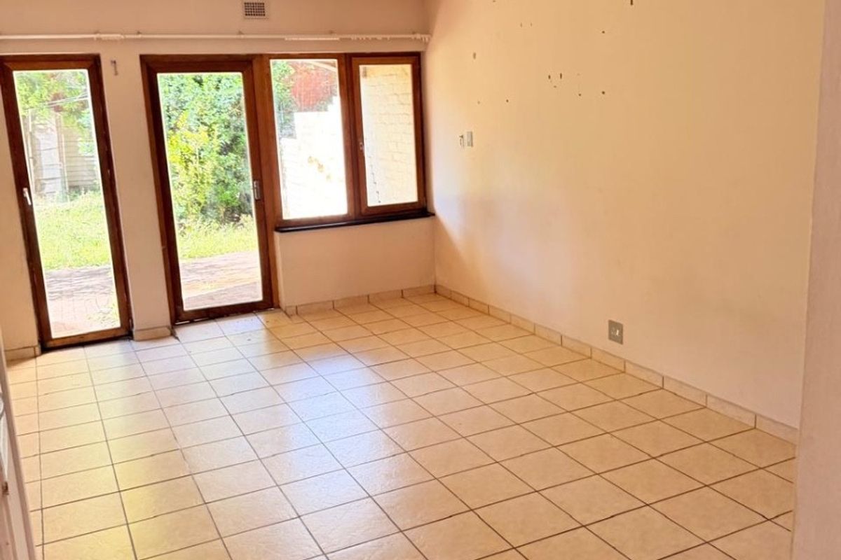 An empty living area featuring tiled flooring, a tongue-and-groove ceiling, and glass doors providing direct access to the outdoor space.