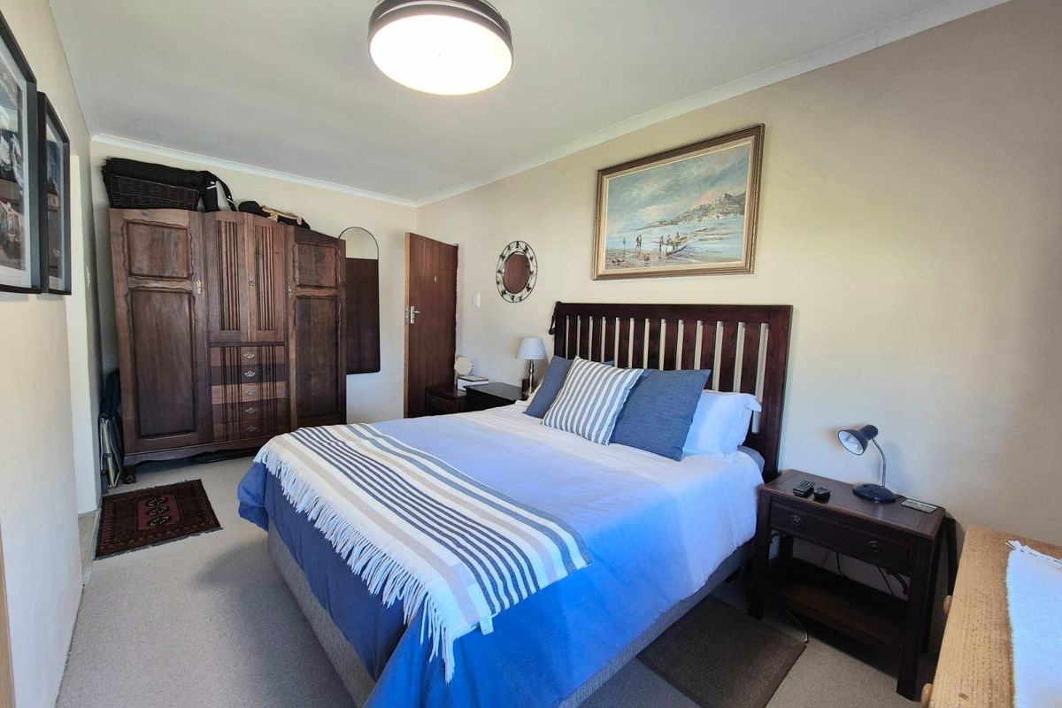 A well-maintained bedroom featuring neutral wall finishes, carpeted flooring, and a central ceiling light fixture.