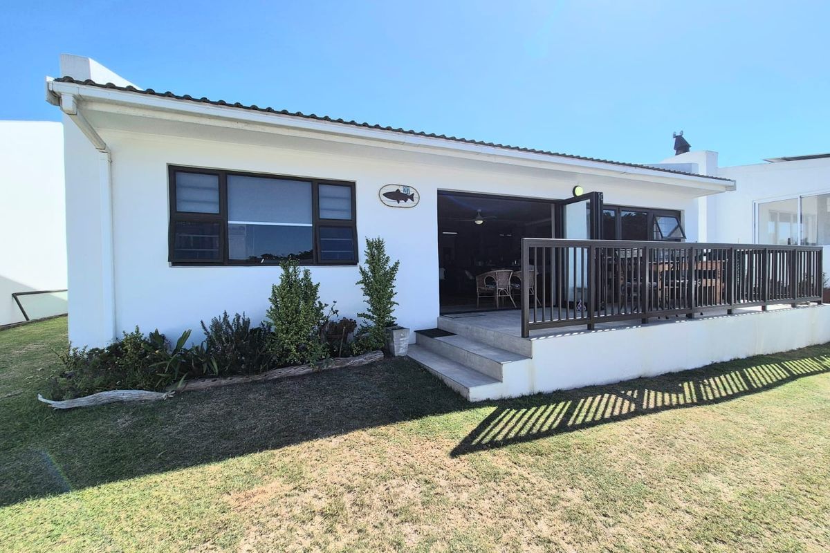 Rear view of the house featuring a raised patio deck with metal railings, accessible via sliding doors from the interior living space.