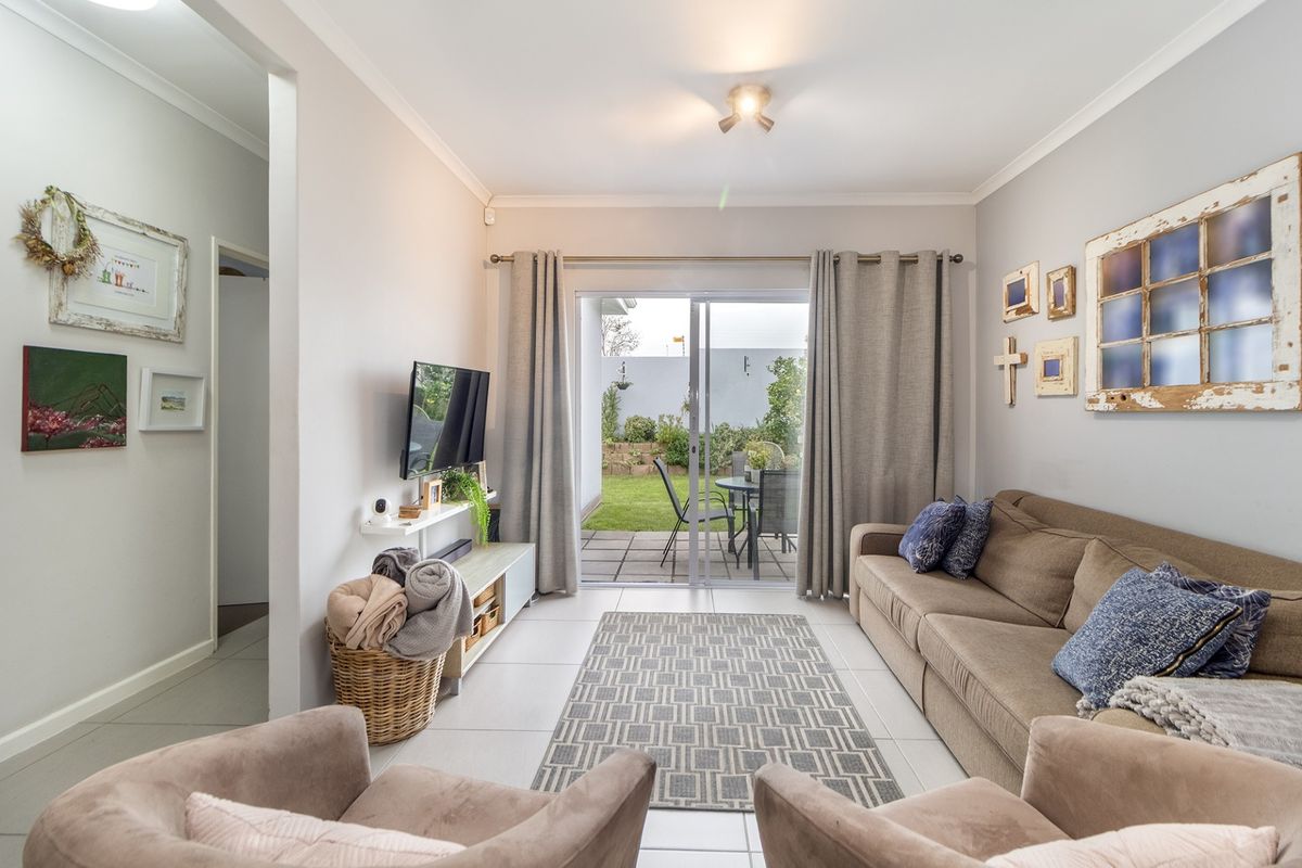 A bright living room featuring tiled flooring and large sliding glass doors that provide direct access to the rear patio and garden.