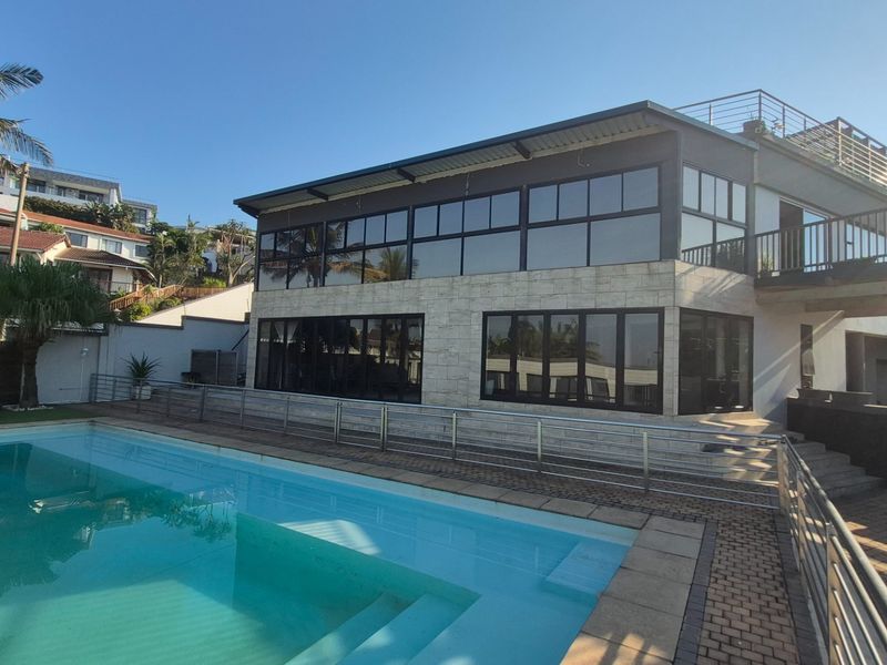 Modern multi-level residence featuring extensive glass facades, a private swimming pool, and a paved terrace area, ideal for outdoor entertaining.
