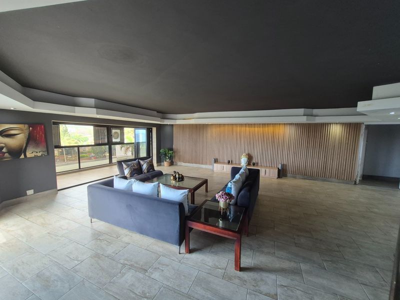 Spacious living area featuring modern tiled flooring, a striking timber slat feature wall, and large sliding glass doors leading to an outdoor space.